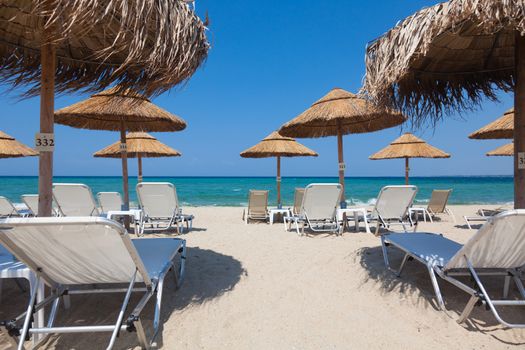 Beautiful beach with deck chairs and umbrellas on the sandy beach in Nea Irakleia (Halkidiki). Thessaloniki - Greece