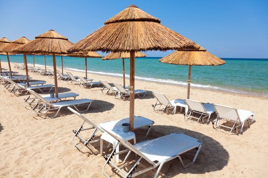 Beautiful beach with deck chairs and umbrellas on the sandy beach in Nea Irakleia (Halkidiki). Thessaloniki - Greece