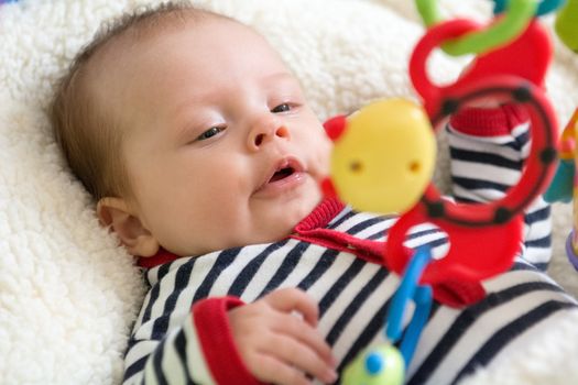 Happy baby girl grabbing a hanging down toy