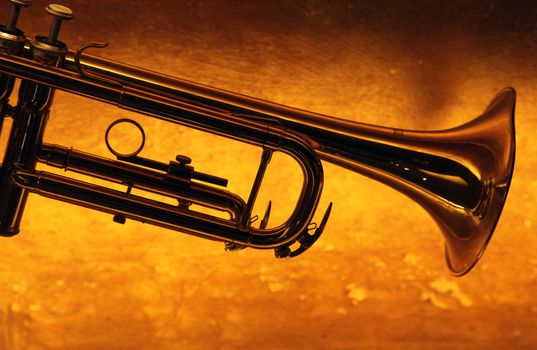 Brass trumpet horn on a golden background. Soft light photograph.