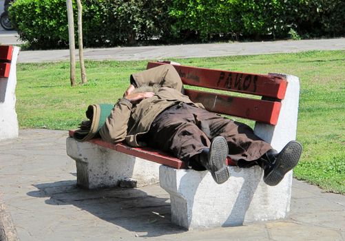 THESSALONIKI, GREECE - MARCH 29: Sleeping homeless man on the bench in a public park on March 29, 2012 in Thessaloniki, Greece. Increase of 25% of the homeless in years 2009-2011 in Greece