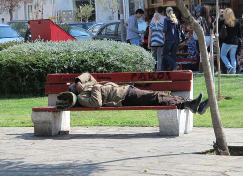 THESSALONIKI, GREECE - MARCH 29: Sleeping homeless man on the bench in a public park on March 29, 2012 in Thessaloniki, Greece. Increase of 25% of the homeless in years 2009-2011 in Greece