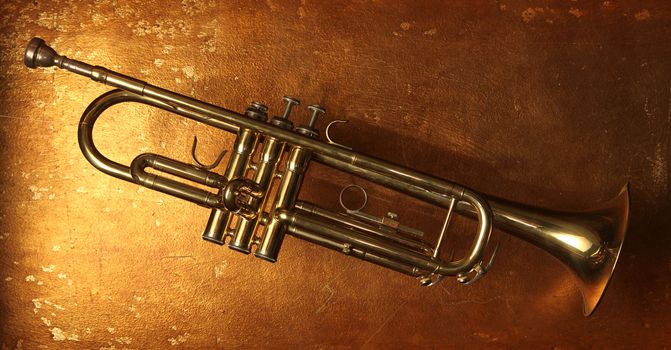 Brass trumpet horn on a golden background. Soft light photograph.