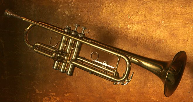 Brass trumpet horn on a golden background. Soft light photograph.