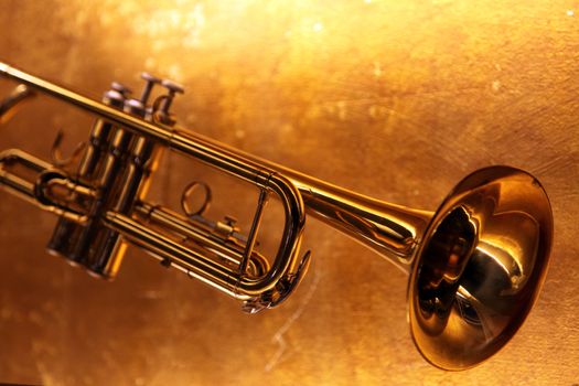 Brass trumpet horn on a golden background. Soft light photograph.