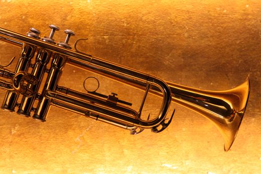 Brass trumpet horn on a golden background. Soft light photograph.