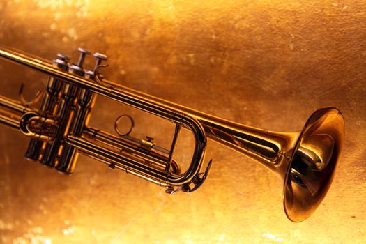 Brass trumpet horn on a golden background. Soft light photograph.