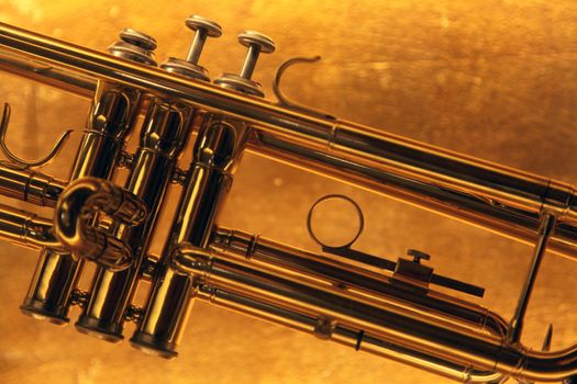 Brass trumpet horn on a golden background. Soft light photograph.