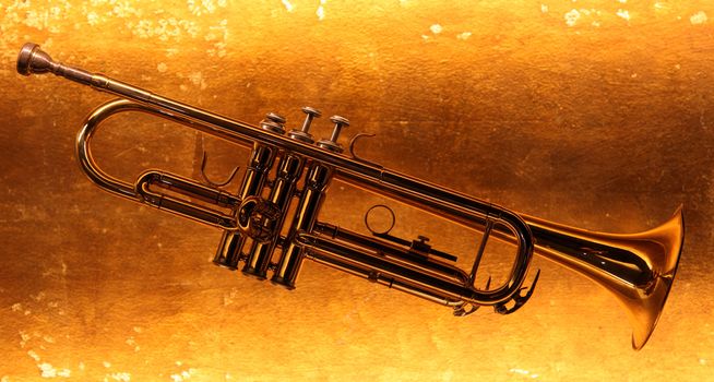 Brass trumpet horn on a golden background. Soft light photograph.