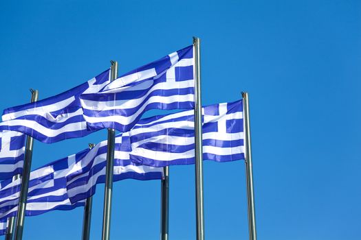 National Greek flags waving in wind against clear blue sky