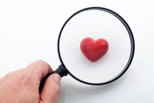 Looking a red heart through a magnifying glass