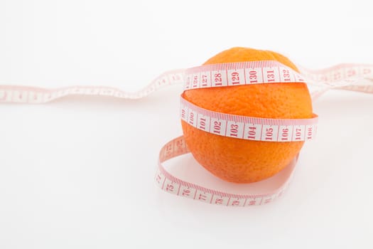 Orange fruit surrounded by a tape measure on white background