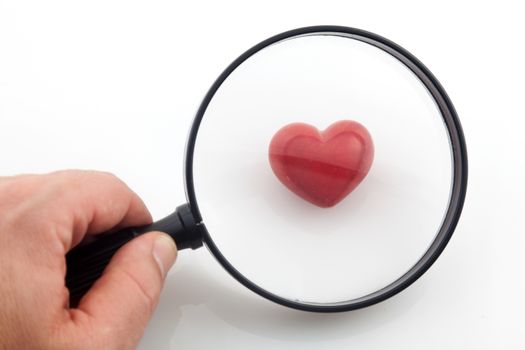 Looking a red heart through a magnifying glass