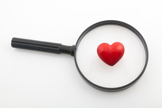 Looking a red heart through a magnifying glass