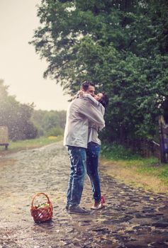 Young couple in Ukrainian style clothes kissing while standing under rain