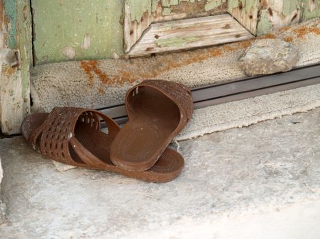 A pair of old plastic slippers at the doorstep outside an old house in Pirgi of Chios island - Greece