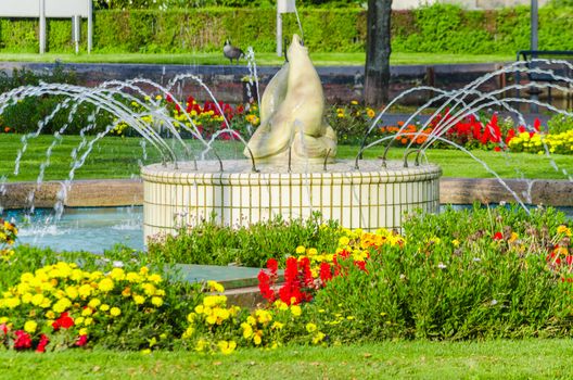 Beautiful fountain in garden with colorful flowers.