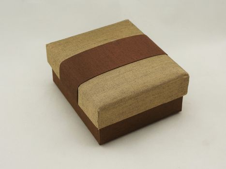 Gift box cover with a lid. The exterior is made from fabric with gold and brown color.                                