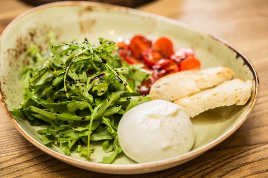 Burrata mozzarella cheese, tomato and bread, selective focus