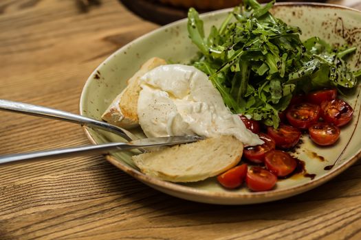 Burrata mozzarella cheese, tomato and bread, selective focus