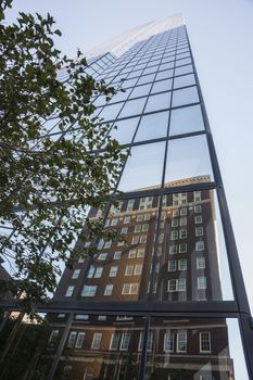 Urban mirror image, Victorian style brick building reflected in mirror glass facade of modern high  rise Boston building.