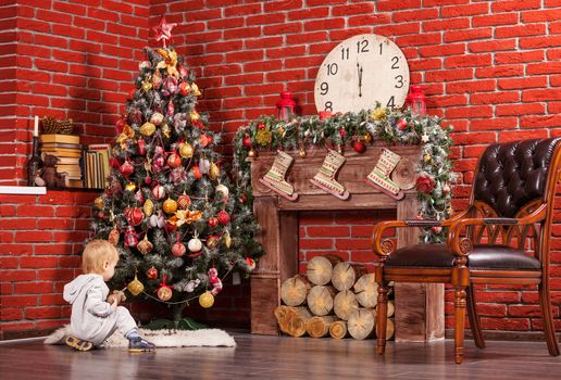 Blonde toddler boy playing near Christmas tree