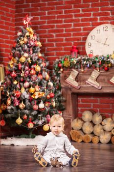 Cheerful little boy playing with his toy animals by Christmas tree