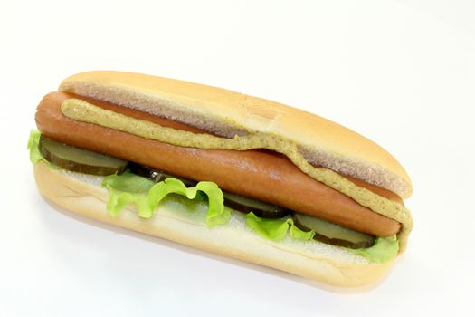 a hot dog with pickle and salad against white background