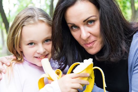 Photo of mother and daughter eating banana