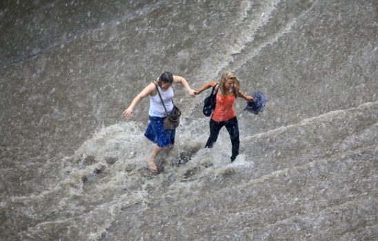 Thessaloniki, Greece - June 15, 2011: People try to cross a flooded road in the center of city. The summer months are a common phenomenon reason for the poor maintenance of drains