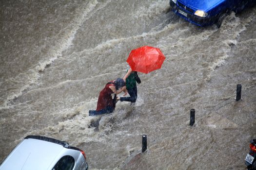 Thessaloniki, Greece - June 15, 2011: People try to cross a flooded road in the center of city. The summer months are a common phenomenon reason for the poor maintenance of drains