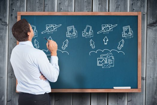 Thinking businessman holding pen against blackboard with technology doodles