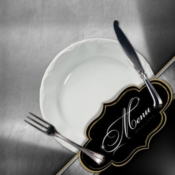Restaurant menu with empty white plate and silver cutlery, on metallic background with diagonal band and empty black label