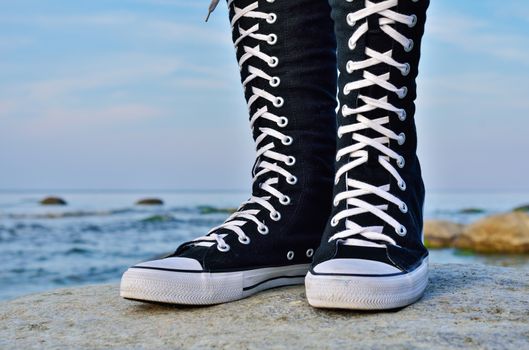 Teenager's foots in gumshoes on the sea coast