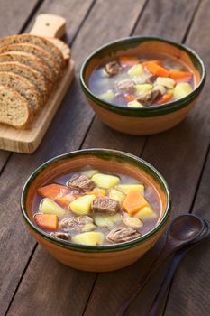 Two bowls of traditional Hungarian soup called Gulyasleves made of beef, potato, carrot, onion, csipetke (homemade pasta) and seasoned with salt and paprika (Selective Focus, Focus in the middle of the soup in the first bowl)