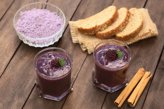 Ecuadorian traditional thick drink called Colada Morada, prepared by cooking purple corn flour and different fruits (for example strawberry, pineapple, naranjilla, grape, babaco, blackberry, etc) and seasoned with panela (cane sugar), cinnamon, allspice and cloves; accompanied by bread (Selective Focus, Focus on the blackberry on the left drink)