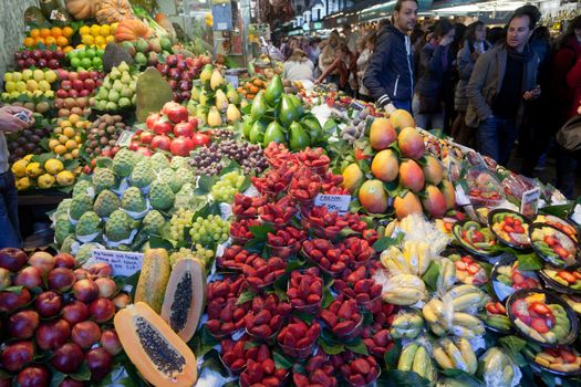 BARCELONA, SPAIN - APRIL 14: Unidentified tourists in famous La Boqueria market with Jamon, vegetables and fruits on April 14, 2012 in Barcelona, Spain. One of the oldest markets in Europe that still exist. Established 1217.