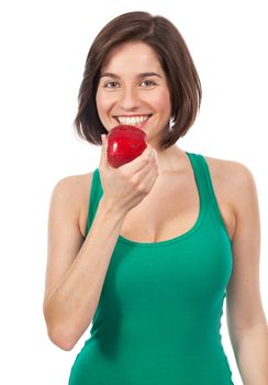 Beautiful young brunette eating a red apple, isolated on white
