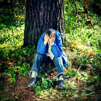 Sorrowful Teenager sitting in the Forest