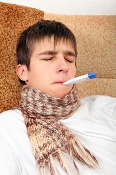 Sick Teenager with Thermometer on the Sofa at the Home