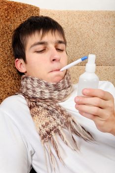 Sick Teenager with Thermometer and Drug on the Sofa at the Home