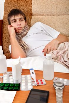 Sad and Sick Teenager on the Sofa at the Home with Pills on foreground