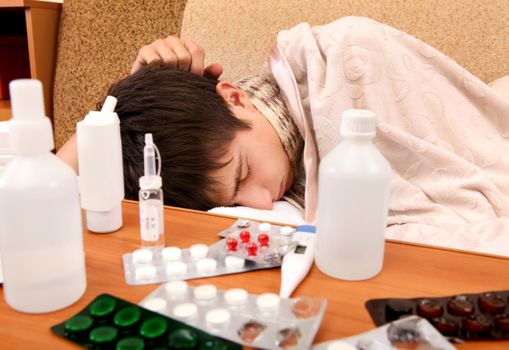 Sick Teenager sleep on the Sofa with Pills on foreground