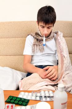 Sick Teenager on the Sofa at the Home with Pills on foreground