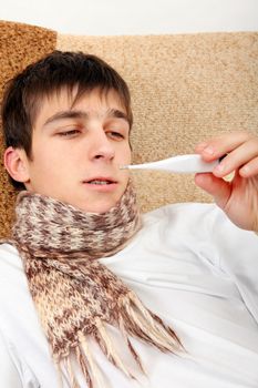 Sick Teenager with Thermometer on the Sofa at the Home