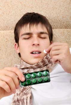 Sick Teenager taking a Pill on the Bed at the Home
