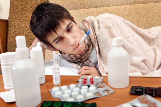 Sick Teenager on the Sofa at the Home with Pills on foreground