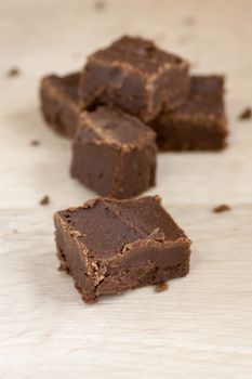 Handmade fudge cut for packaging on a wooden cutting board.