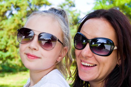 Photo of smiling mother and daughter in sunglasses