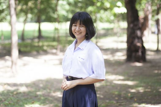 Asian female student Smiling and standing in the park.